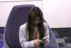Senior Lilian Tran uses her phone while sitting down in the senior academy. 